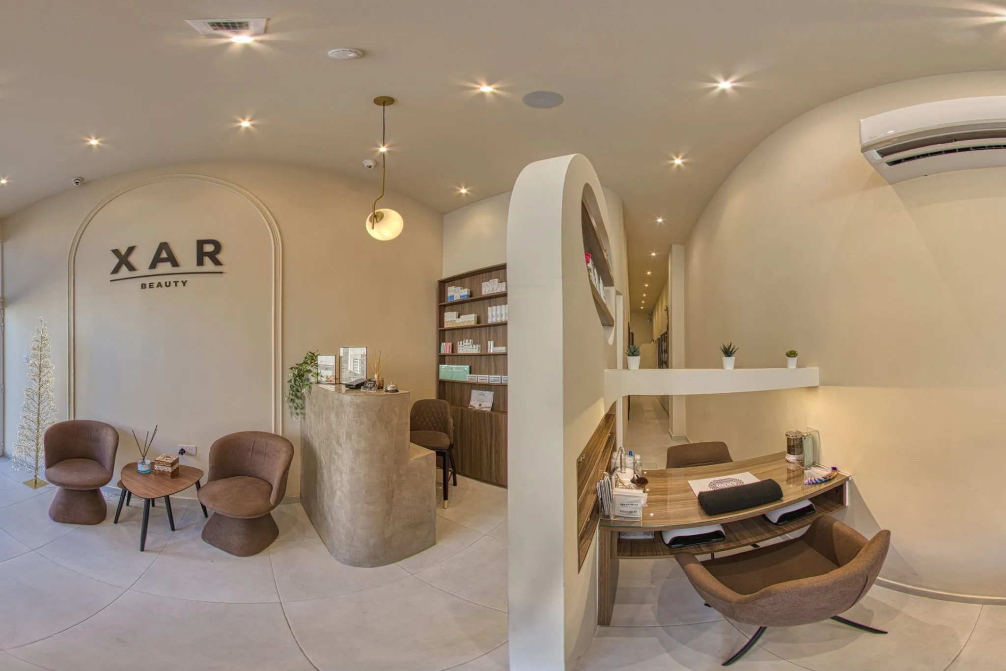 Reception at XAR Beauty: arched alcove with the XAR Beauty wall sign, low chairs and a product shelf