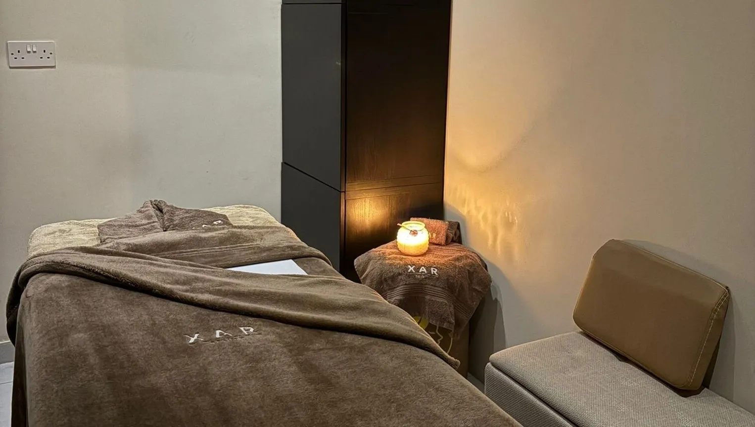 A made-up treatment bed at XAR Beauty under warm candlelight, XAR towels folded beside it